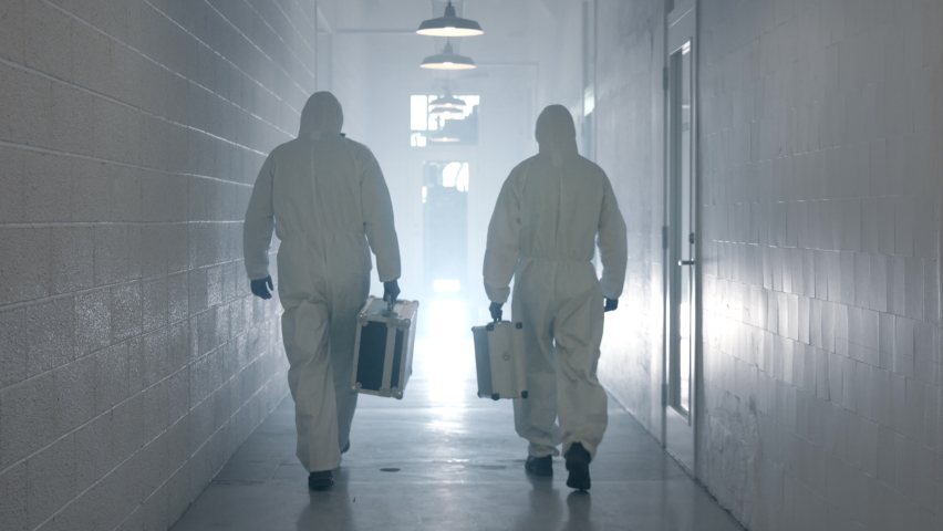 Laboratory Workers Walking in Corridor. Laboratory workers with Cases in Hands Wearing Chemical Suit and Masks Royalty-Free Stock Footage #1059468221