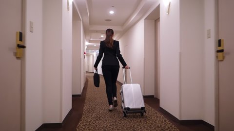 Business woman go behind time, run with laptop bag and small suitcase at empty corridor. Moving camera follow behind, slow motion shot