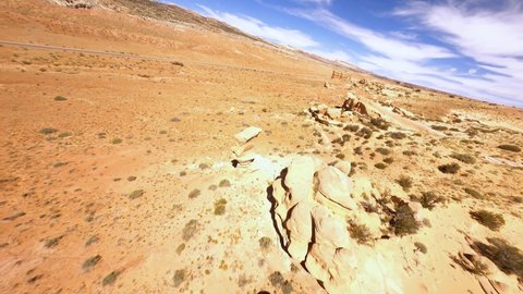 Aerial, FPV, drone shot low, over desert, rocks and sandstone formations, bright, sunny day, near Capitol reef, in Utah, USA