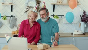 Lockdown. Social distance. Cheerful caucasian old grandparents speaking with family on laptop videochat congratulate with birthday anniversary holding gift card. Holidays concept.