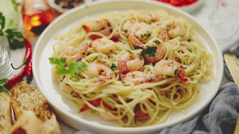 Spaghetti with shrimps on white ceramic plate and served with glass of white wine. Various fresh ingredients on sides. Top view, flat lay.