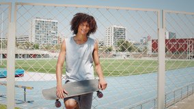 Hispanic latin young man holding skateboard and smiling, portrait of happy skater in skatepark spain, barcelona, brazilian male professional skateboarder - Powered by Shutterstock - Get 15% off with code: PIKWIZARD15