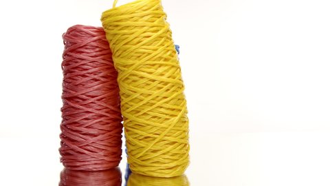 Three skeins of colorful recycled plastic twine rotating on isolated white background. Hank of nylon rope knot strings in motion. Eco-friendly materials, ecology concept. Copy space