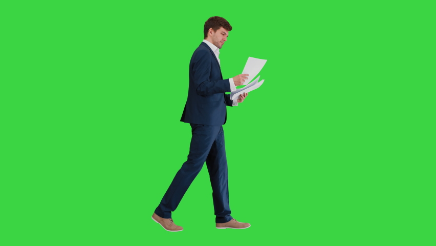 Concentrated Businessman reading documents or report while walking on a Green Screen, Chroma Key. Royalty-Free Stock Footage #1059494468