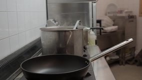 Detail of the hands of a chef moving a pot in the kitchen of a restaurant