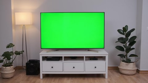 big screen green screen television on white console in simple modern living room
the camera is making a slide