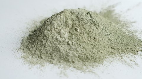 close up green clay powder rotates on white background