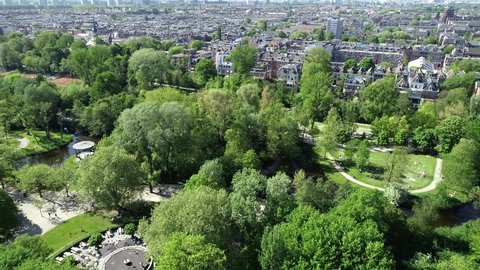 Vondelpark in Amsterdam, Netherlands. Aerial view of famous place, public park Vondelpark . Sunny day in summer or spring. People are resting and relaxing on green grass around lake.