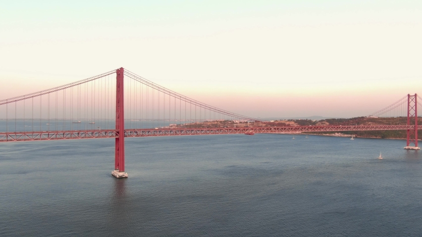 Aerial close up view of Lisbon Ponte 25 de Abril suspension bridge cars driving at sunset, Portugal Royalty-Free Stock Footage #1059506072