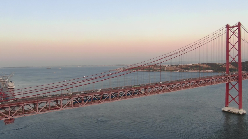 Aerial close up view of Lisbon Ponte 25 de Abril suspension bridge cars driving at sunset, Portugal Royalty-Free Stock Footage #1059506075