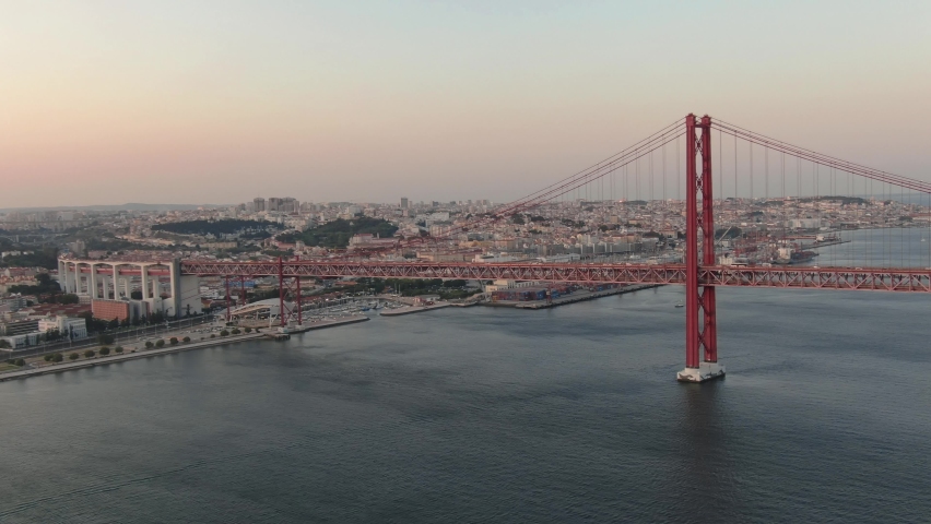Aerial close up view of Lisbon Ponte 25 de Abril suspension bridge cars driving at sunset, Portugal Royalty-Free Stock Footage #1059506078