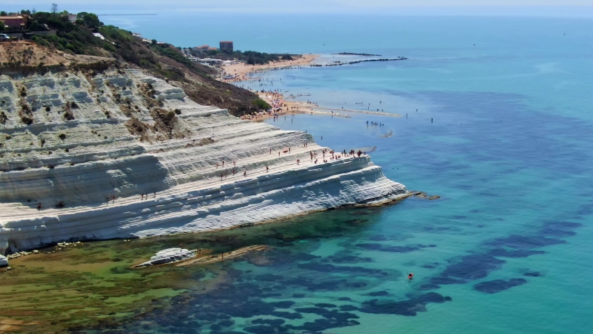 Tourists explore and sightsee iconic Scala dei Turchi, Sicily, Italy, Europe, aerial shot