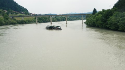 Muta / Slovenia - 09 05 2019: Aerial push in towards wooden raft floating on river Drava, slovenia