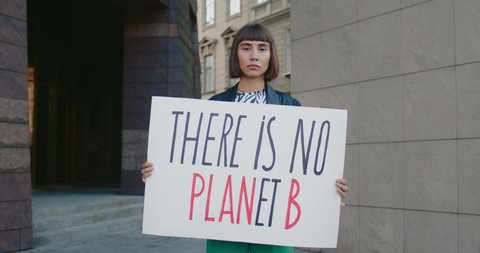 Young female holding there is no planet b phrase cardboard while standing at city street. Female student acrivist supporting eco campaign. Concept of environmental protection. Zoom in.