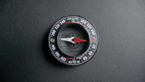 a modern compass lying on a black desk with a red arrow that shows the direction. Concept of travel, adventure, expedition, business, choice and possibilities. 4k