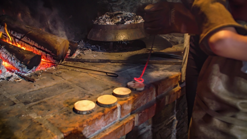 Close up shot of a kid marking a heart on a piece of wood with a red hot iron stick and wearing gloves