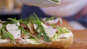 preparing food in the home kitchen. cooking Breakfast or lunch in the restaurant. Fast food close-up. A male chef pours pesto over a large sandwich with cheese cucumber ham and salad - Powered by Shutterstock - Get 15% off with code: PIKWIZARD15