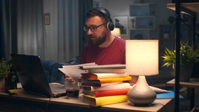 Man Discussing Financial Issues via Video Conferencing at Home at His Desk at Midnight
