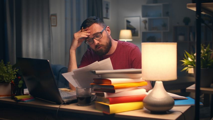 A man experiences difficulties due to fatigue while working late at night | Shutterstock HD Video #1059520259