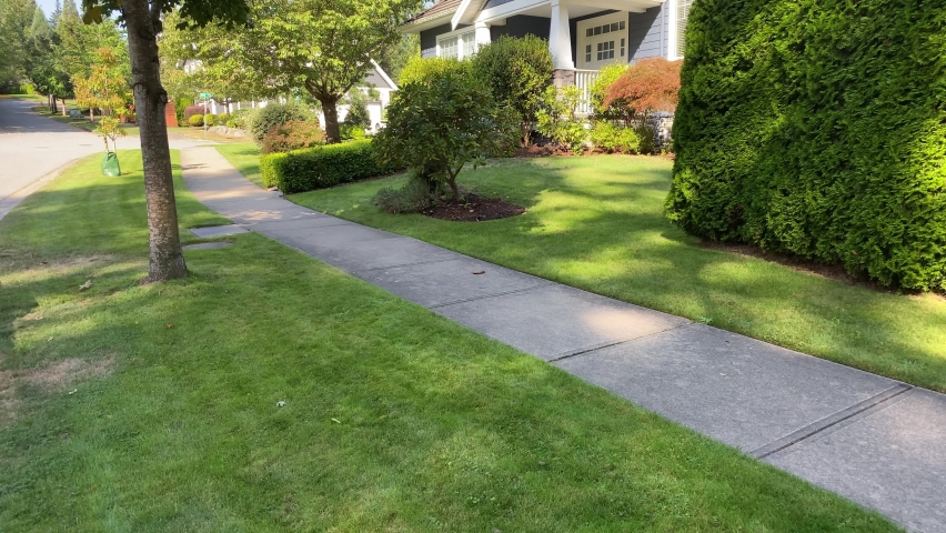 Establishing shot of blue painted wood luxury house with trees and nice landscape in the street of Vancouver, Canada, North America. Blue sky white clouds. Day time on September 2020. Tilt up. H.264.