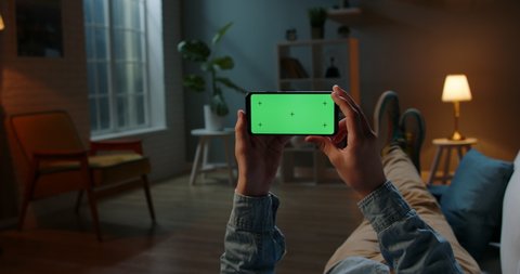 Close up shot of guy using his horizontal smart phone with mock up green screen at night, using various gestures while watching a video 4k video template