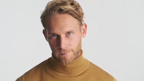 Handsome blond bearded man confidently looking in camera over white background. Male model posing in studio