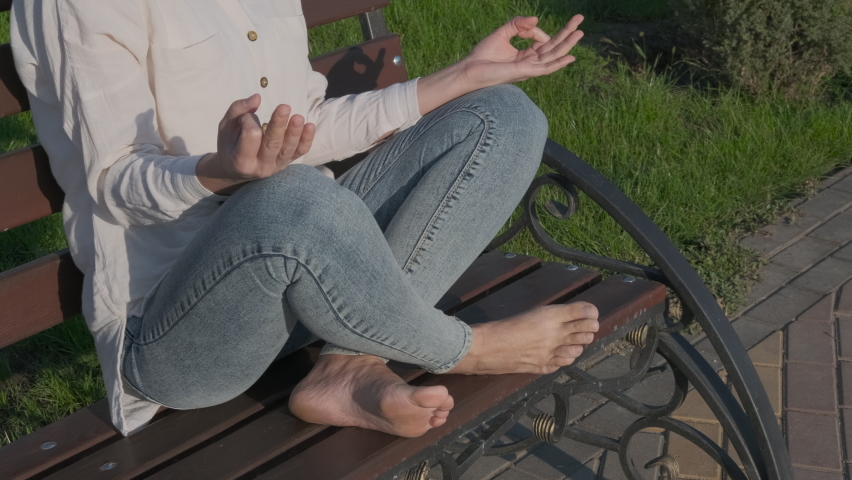 Yoga position on the bench. A view of a female in yoga asana on the bench in the summer park.