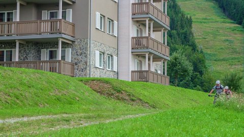 Ribnica na pohorju , Ribnica na pohorju / Slovenia - 08 14 2019: Young riders, riding their mountain bikes through path beside residential building