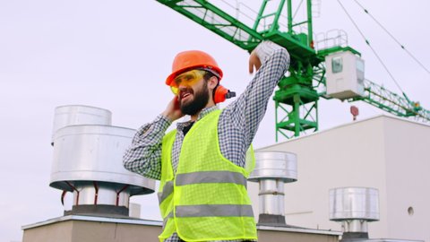 Charismatic engineer man dancing and feeling excited on top of construction site he wearing all equipment for safety in front of the camera