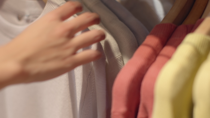 Close-up of female hands plucked hanger Choosing clothes in a clothing store. woman hand runs across a rack of clothes buying Clothes in a shopping mall. Sale Promotion and Shopping Concept. Royalty-Free Stock Footage #1059540842