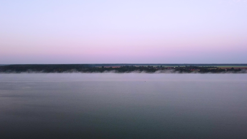Flying morning fog over the lake at sunrise