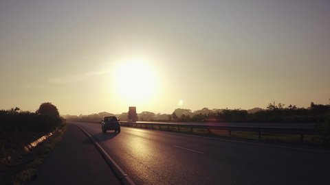 Main road at sunset. Cars and trucks cars are passing by highway to their destination.