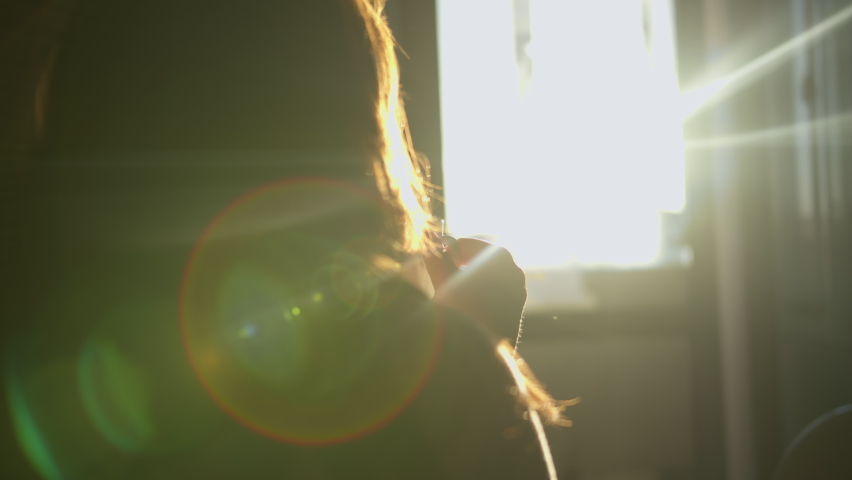 silhouette of woman sitting in the kitchen and enjoying morning coffee, steam from a glass