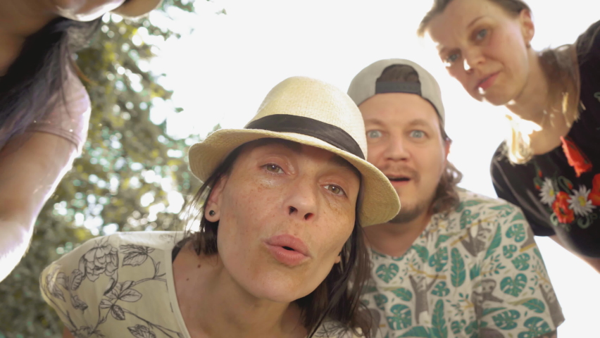 Company of adults in headgear look at the camera in the street. They smile and point fingers. Emotions of interest. High quality 4k footage.