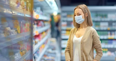 Girl in a protective medical mask comes to the freezer shelf and selects products. Girl takes eggs from the grocery shelf in the supermarket. 4k, ProRes