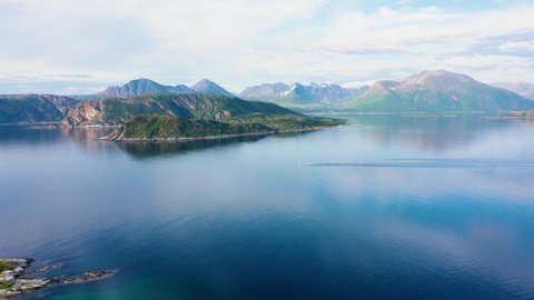 Aerial view over motorboats,on the Arctic ocean, fjord mountains in the background. sunny, summer day, in Sommaroy, North Norway - tracking, drone shot
