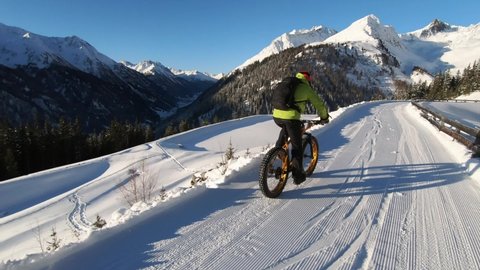 MTB Mountainbiking in the snow. Biking with MTB high up in the mountains in Winter. Fatbike tour with a guide. Beautiful mountain view Tirol.