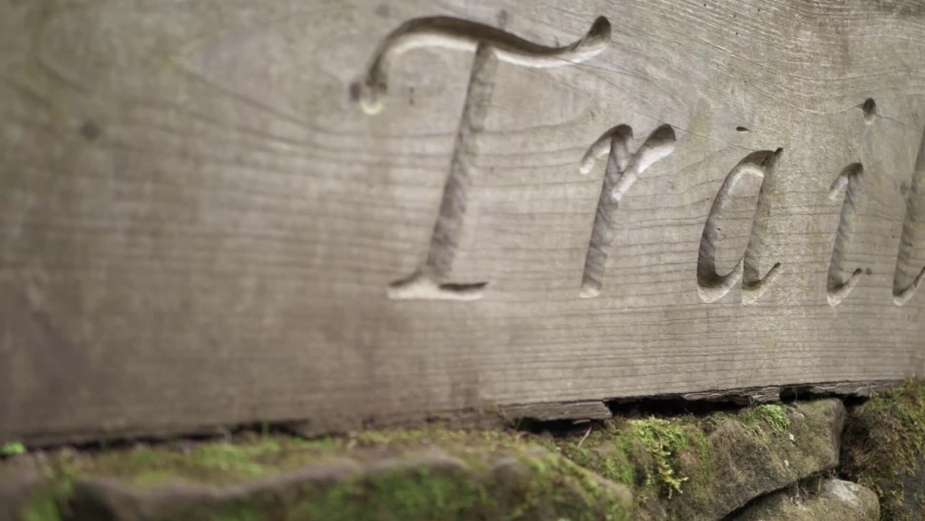 Wooden carved sign pointing hikers to trail close up shot