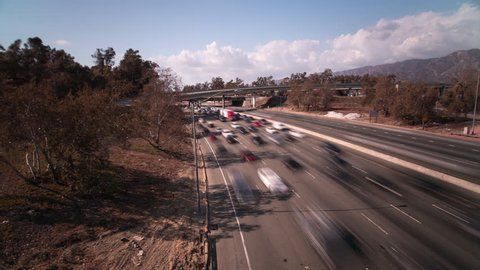 Hyperlapse of Freeway in Los Angeles, California from an overpass on a bright sunny day.  Lots of traffic driving by.