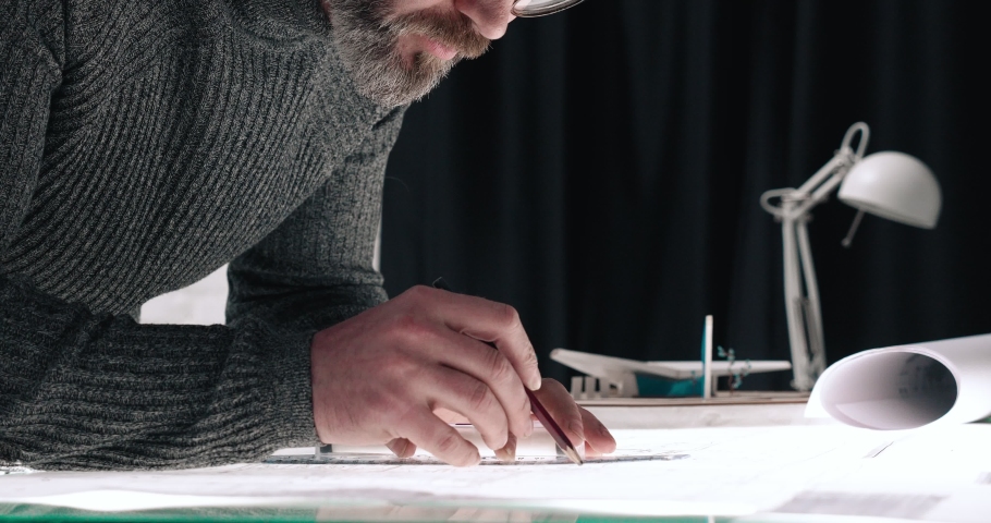 Man Engineer making Drawings and Blueprints of Building.  Man Architect in eyeglasses drawing with pencil in modern office | Shutterstock HD Video #1059571175