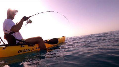 Mil Palmeras beach, Spain, August 24, 2020: Kayak fishing, trolling fishing. A sportsman fishing in kayak underwater view of fish hooked to a lure being pulled out of water.