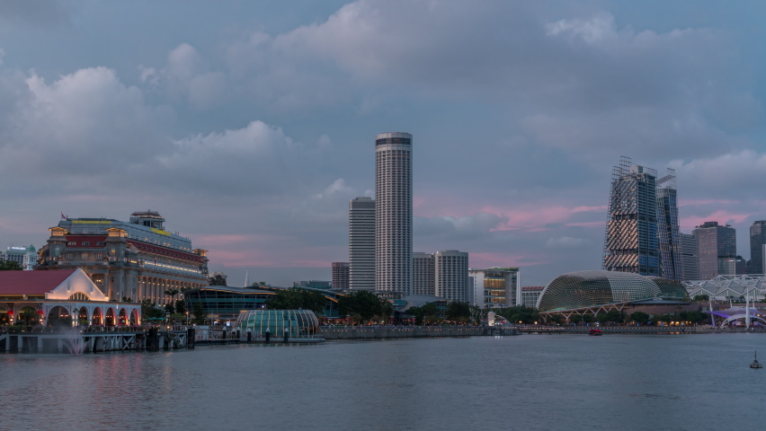 City skyline with skyscrapera and Esplanade Theatres on the Bay in Singapore at dusk, with beautiful reflection in water day to night transition timelapse. Boats floating on water