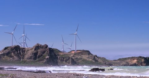 White wind mill turbines on sea coast generate green energy at clear day with blue sky
