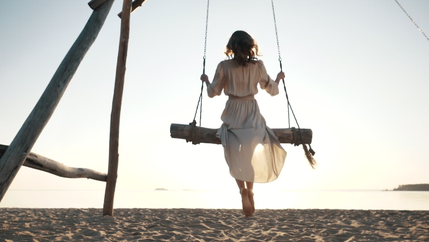 Back View at Young Resting woman Enjoying Freedom Feel, Swaying Sitting on Swings Near Sea Beach Alone in Sunshine. Serene Incredible Summer Relax, Paradise Dream Happiness on Beautiful Resort Outdoors | Shutterstock HD Video #1059583295
