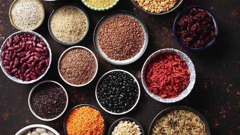 Various superfoods in smal bowls on dark rusty background. Superfood as rice, lentil, beans, peas, goji, flaxseed, buckwheat, couscous, chickpeas Top view Flat lay