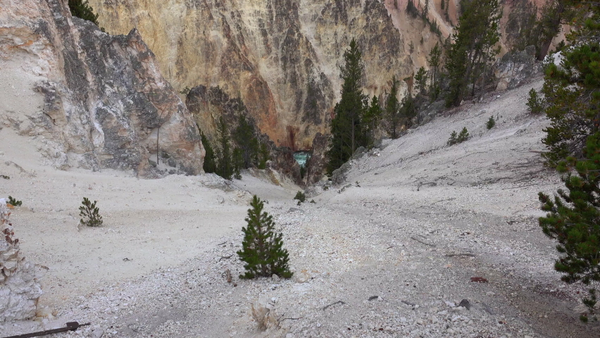 Looking down a scree field. Camera zooms in on a section of the Yellowstone River seen between two cliff faces.