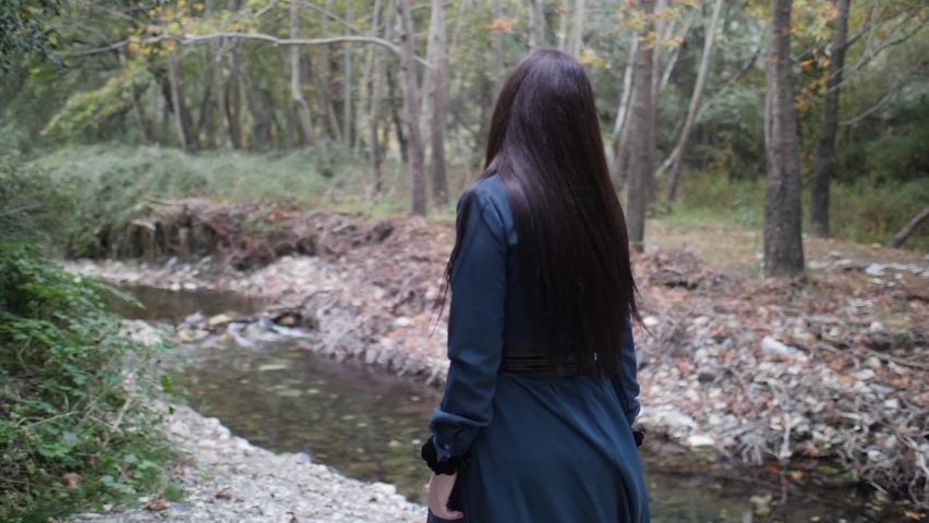 A beautiful gothic model dances and spins in slow motion in the woods.