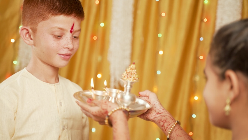 Shoulder shot, Sister offering aarati to Brother during Bhai Dooj or Bhaubeej Indian religious festival ceremony