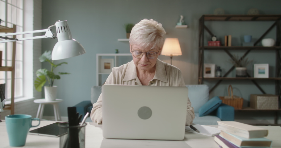 Pleased mature caucasian woman finishing her work. Remote senior worker closing her laptop and leaning on back of chair, joyfully smiling 4k footage Royalty-Free Stock Footage #1059593765