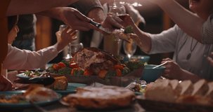 People having a thanksgiving dinner party. Close up shot of table filled with salads and tasty roasted turkey. Family filling up plates with food 4k footage
